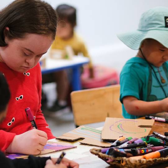 Two children using crayons at a craft table